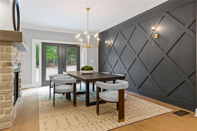 12995 Bucksport Dr, Roswell, GA 30075 - dining space with a decorative wall, a chandelier, light wood-style floors, a fireplace, and crown molding