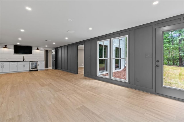 12995 Bucksport Dr, Roswell, GA 30075 - unfurnished living room featuring a decorative wall, wine cooler, light wood-style flooring, bar, and recessed lighting