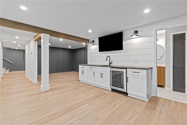 12995 Bucksport Dr, Roswell, GA 30075 - kitchen featuring wine cooler, a sink, light wood-style flooring, white cabinets, and baseboards