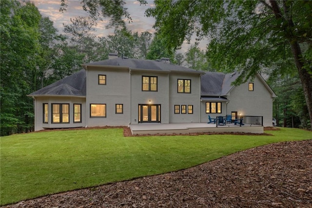 12995 Bucksport Dr, Roswell, GA 30075 - back of house at dusk featuring a yard, stucco siding, and a chimney