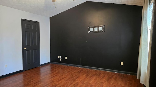 empty room with ceiling fan, lofted ceiling, and dark hardwood / wood-style floors