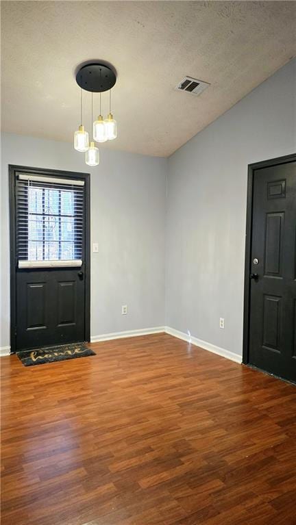 entrance foyer featuring vaulted ceiling, hardwood / wood-style floors, and a textured ceiling