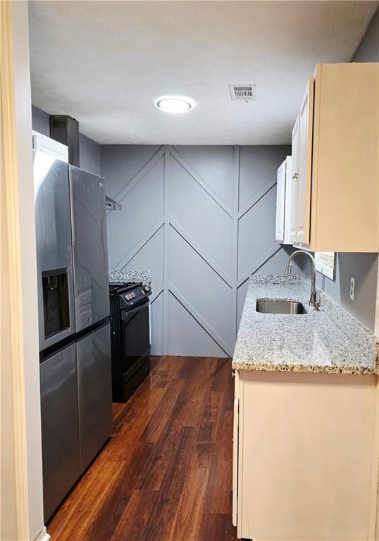kitchen featuring appliances with stainless steel finishes, dark hardwood / wood-style floors, sink, white cabinets, and light stone counters