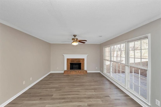 unfurnished living room with a brick fireplace, hardwood / wood-style flooring, a textured ceiling, and ceiling fan