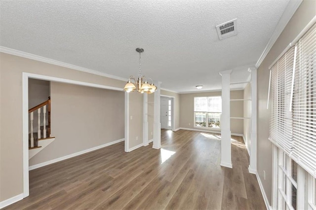 unfurnished dining area featuring ornate columns, dark hardwood / wood-style flooring, ornamental molding, a textured ceiling, and an inviting chandelier