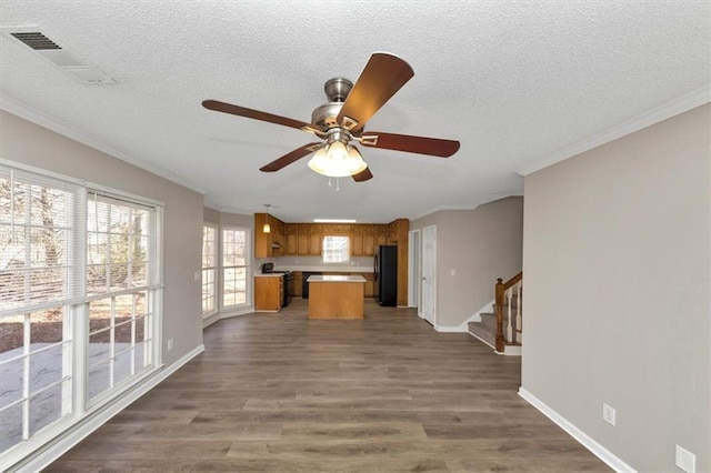 kitchen featuring crown molding, dark hardwood / wood-style floors, a center island, and black fridge