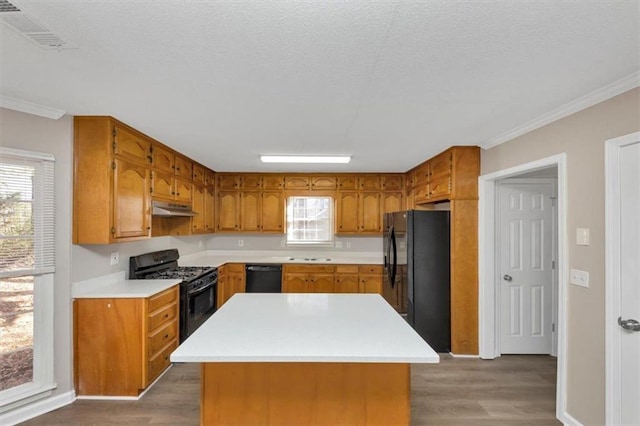 kitchen with hardwood / wood-style flooring, crown molding, a center island, and black appliances