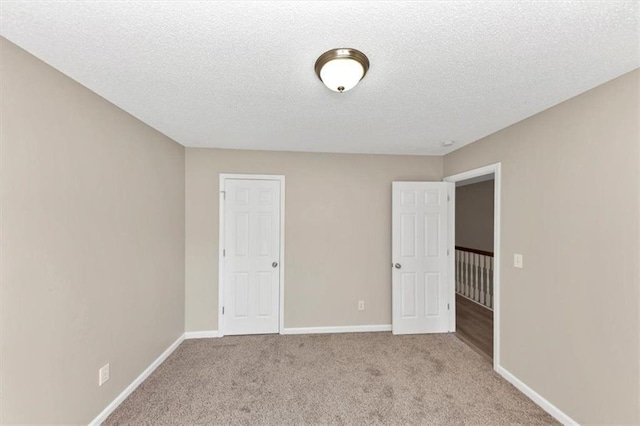 spare room featuring light colored carpet and a textured ceiling