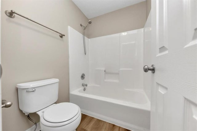 bathroom with wood-type flooring, tub / shower combination, and toilet