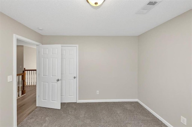 unfurnished bedroom featuring a textured ceiling and carpet