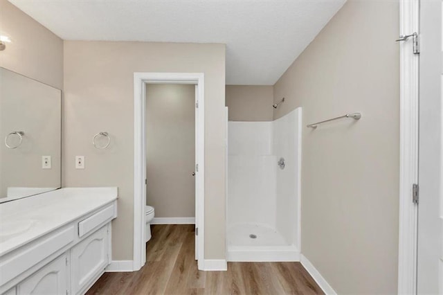 bathroom with walk in shower, vanity, toilet, and hardwood / wood-style floors