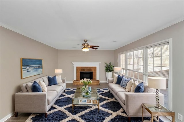 living room featuring crown molding, ceiling fan, and a brick fireplace