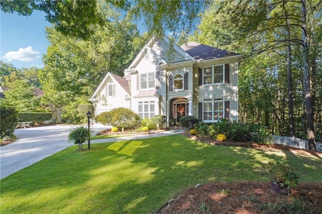 view of front of house with a front yard, concrete driveway, and fence