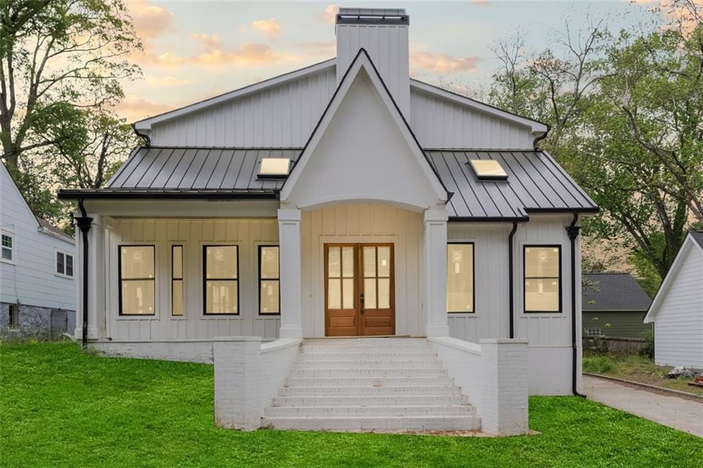 3353 Hemphill St, Atlanta, GA 30337 - back of house at dusk with a standing seam roof, a chimney, a lawn, metal roof, and french doors