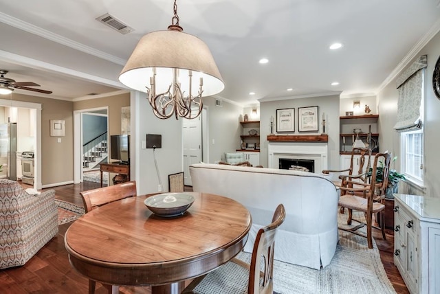 dining area with hardwood / wood-style floors, crown molding, and ceiling fan with notable chandelier