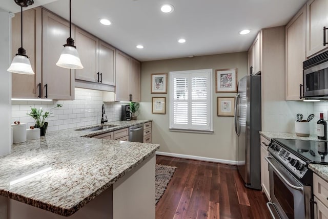 kitchen with pendant lighting, sink, kitchen peninsula, and appliances with stainless steel finishes