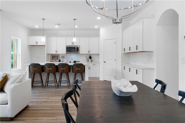 dining space featuring sink, light hardwood / wood-style flooring, and a chandelier