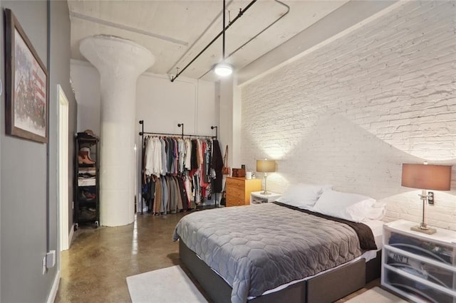 bedroom with concrete flooring and brick wall