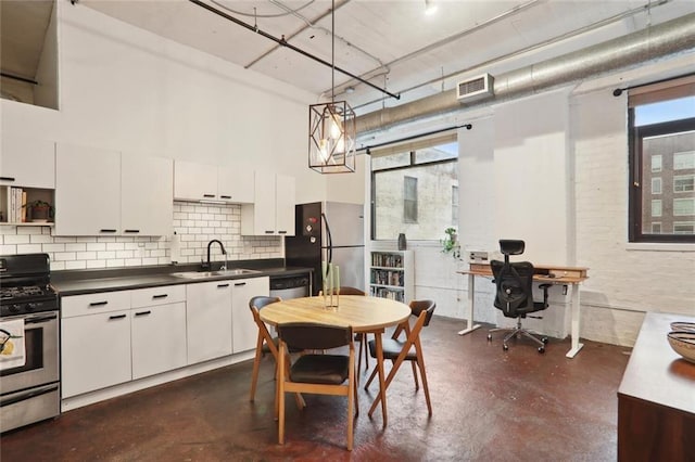 kitchen with backsplash, white cabinets, sink, hanging light fixtures, and stainless steel appliances