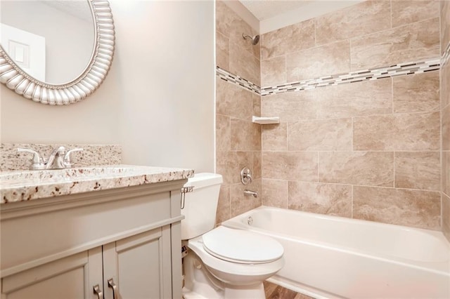 full bathroom with tiled shower / bath, vanity, and toilet