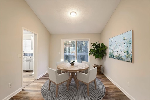 dining space featuring hardwood / wood-style floors and vaulted ceiling