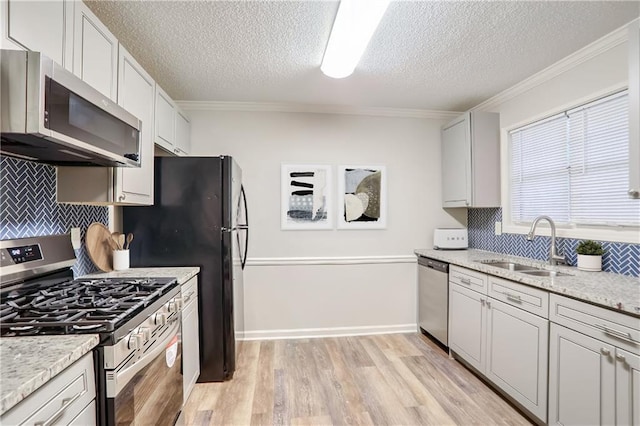 kitchen featuring sink, crown molding, light hardwood / wood-style flooring, tasteful backsplash, and stainless steel appliances