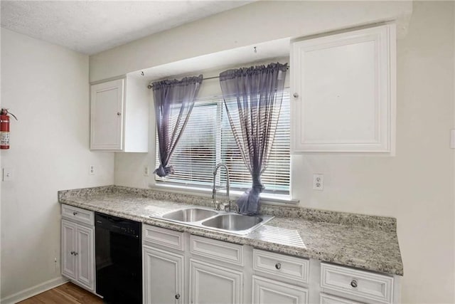 kitchen with dark wood-type flooring, white cabinets, sink, black dishwasher, and a healthy amount of sunlight