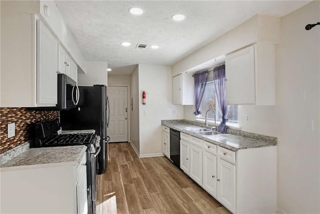 kitchen featuring gas range, sink, dishwasher, white cabinets, and light hardwood / wood-style floors