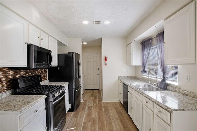 kitchen featuring sink, white cabinetry, stainless steel appliances, and light wood-type flooring