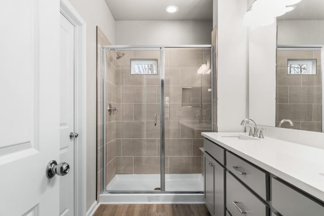 bathroom featuring vanity, wood-type flooring, and a shower with door