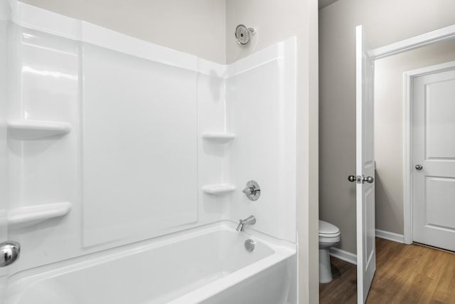 bathroom featuring hardwood / wood-style flooring, bathing tub / shower combination, and toilet