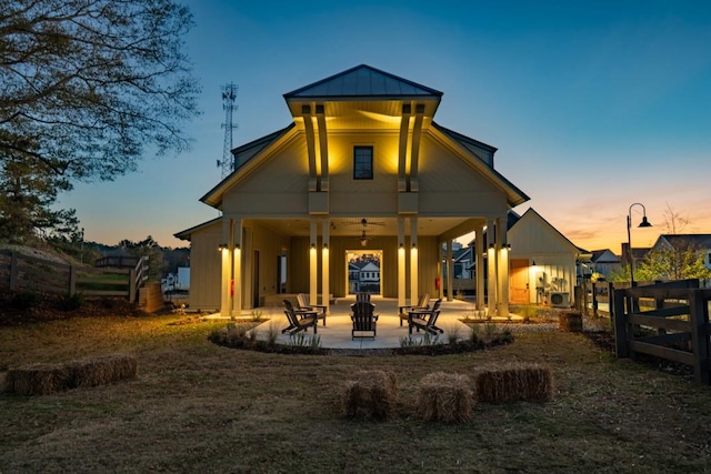 back house at dusk with ceiling fan and a patio