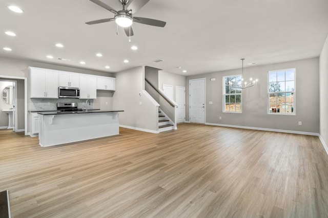 kitchen featuring appliances with stainless steel finishes, decorative light fixtures, white cabinetry, sink, and light wood-type flooring