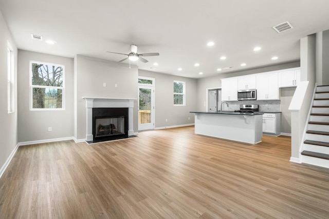 unfurnished living room featuring sink, ceiling fan, and light wood-type flooring