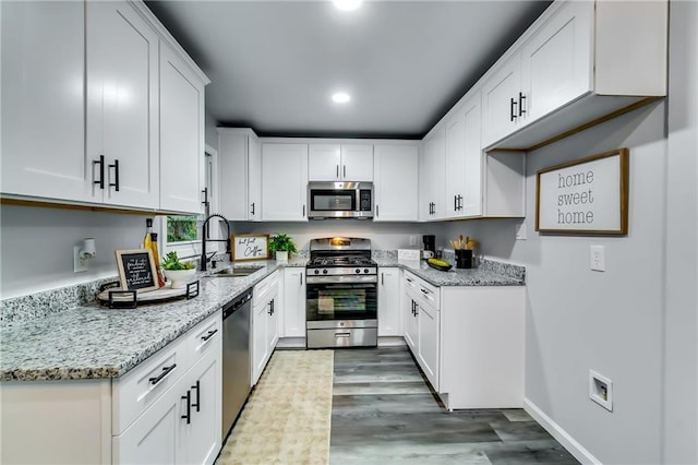 2162 Westover Dr, Atlanta, GA 30344 - kitchen featuring stainless steel appliances, a sink, light stone countertops, white cabinetry, and wood finished floors