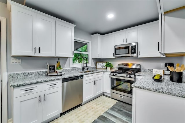 2162 Westover Dr, Atlanta, GA 30344 - kitchen featuring stainless steel appliances, light wood-style flooring, white cabinetry, a sink, and light stone counters