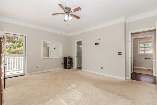 spare room with a ceiling fan, baseboards, crown molding, and light colored carpet