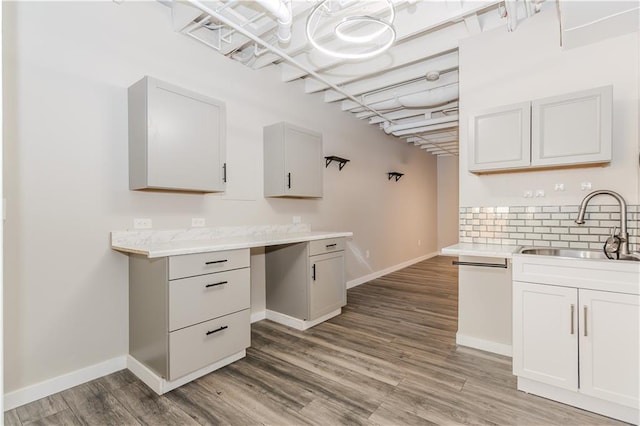 kitchen with light countertops, wood finished floors, a sink, and white cabinetry