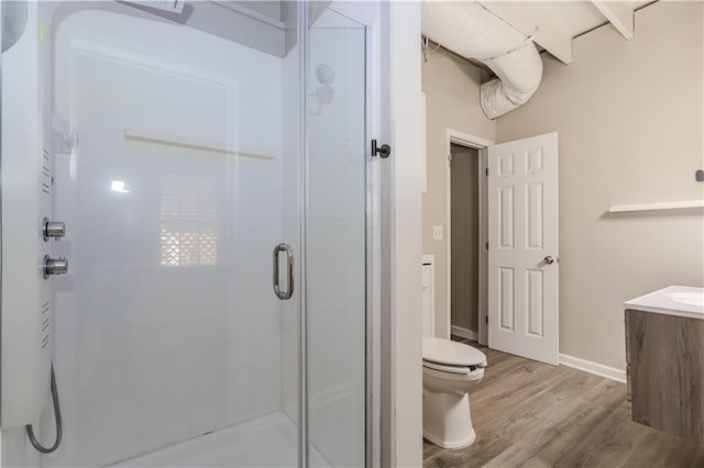 full bathroom with toilet, a stall shower, vanity, wood finished floors, and baseboards