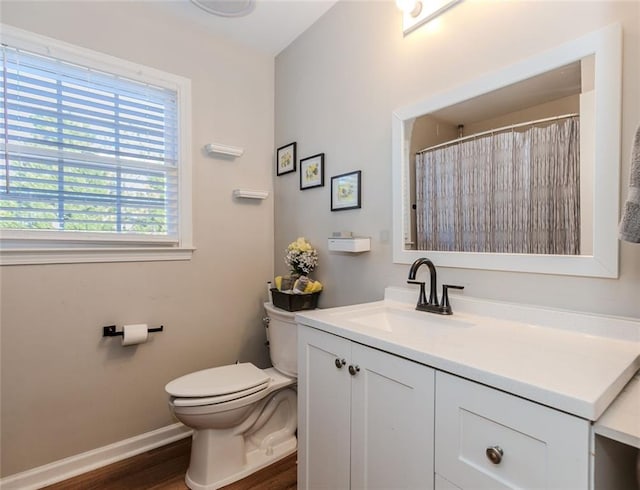 bathroom with toilet, wood finished floors, vanity, and baseboards