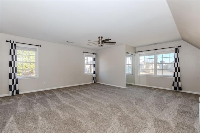 carpeted spare room with lofted ceiling, visible vents, baseboards, and ceiling fan