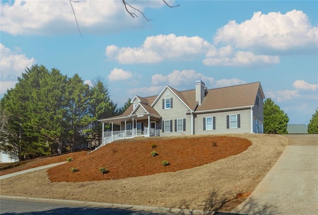 view of front facade featuring a porch, concrete driveway, and a chimney