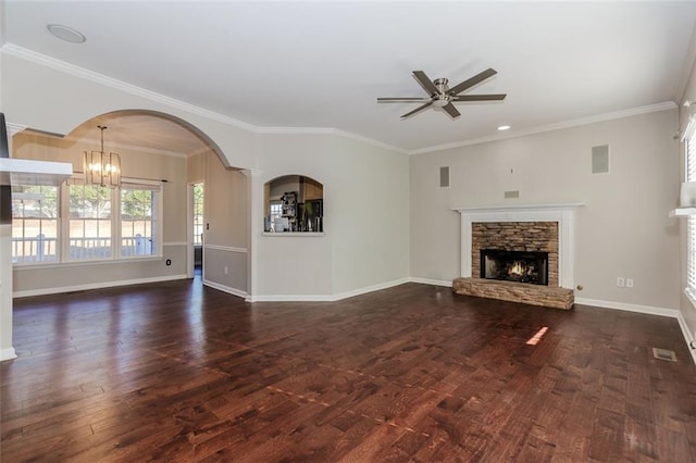 unfurnished living room featuring ceiling fan with notable chandelier, dark wood-style flooring, a fireplace, baseboards, and crown molding