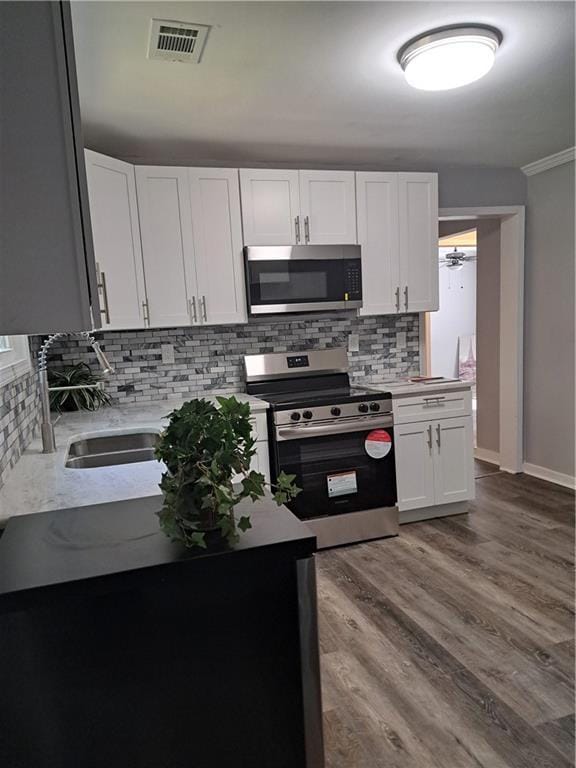 1290 Elizabeth Ave, Atlanta, GA 30310 - kitchen with backsplash, a sink, light countertops, white cabinets, and stainless steel appliances