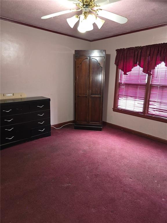 bedroom with wood walls, ceiling fan, crown molding, and multiple windows