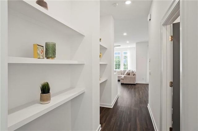 hallway featuring built in shelves and dark hardwood / wood-style flooring