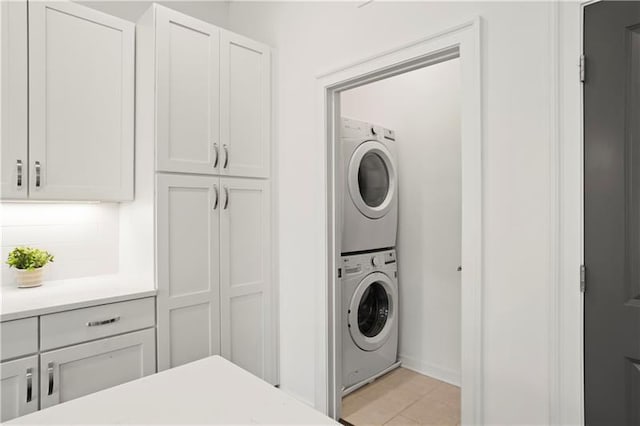 laundry room with stacked washer and dryer and light tile patterned flooring