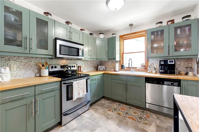 kitchen with a sink, green cabinets, wood counters, and appliances with stainless steel finishes