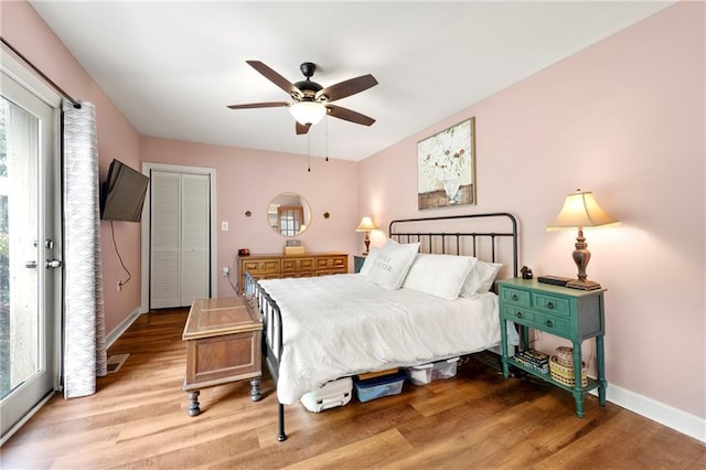 bedroom featuring light wood finished floors, baseboards, and multiple windows