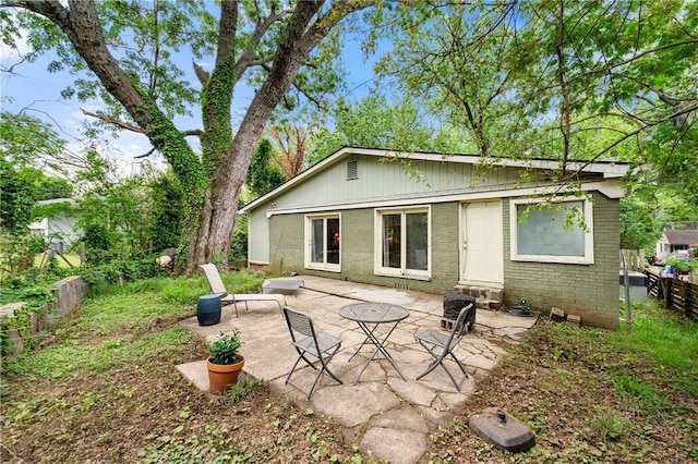 back of house featuring brick siding, fence, and a patio